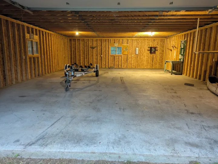 Open interior of the detached garage with concrete floor and boat trailer