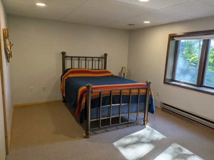 Lower-level bedroom with a bed and large window