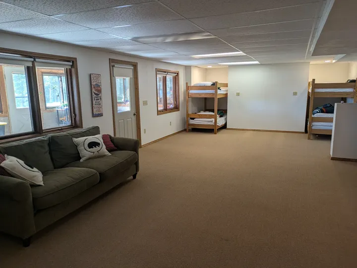 Window-lined lower-level room with a sofa and bunk beds
