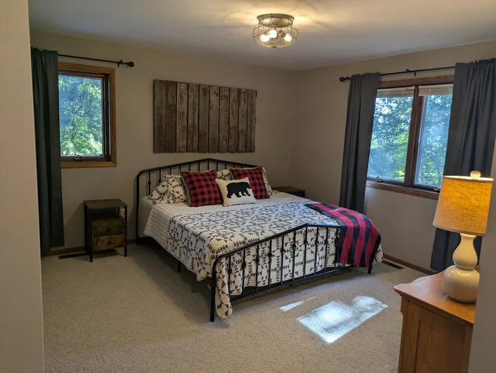 Main-level primary bedroom with a bear accent pillow and windows on two walls