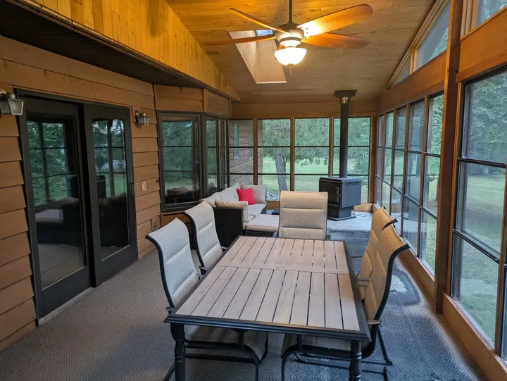 Window-lined sunroom with a wood ceiling, dining table and seating